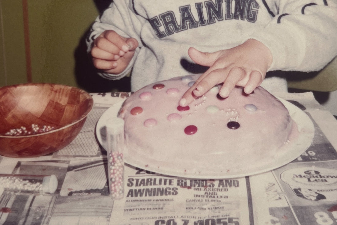 Photo of a child's hand decorating a home made birthday cake