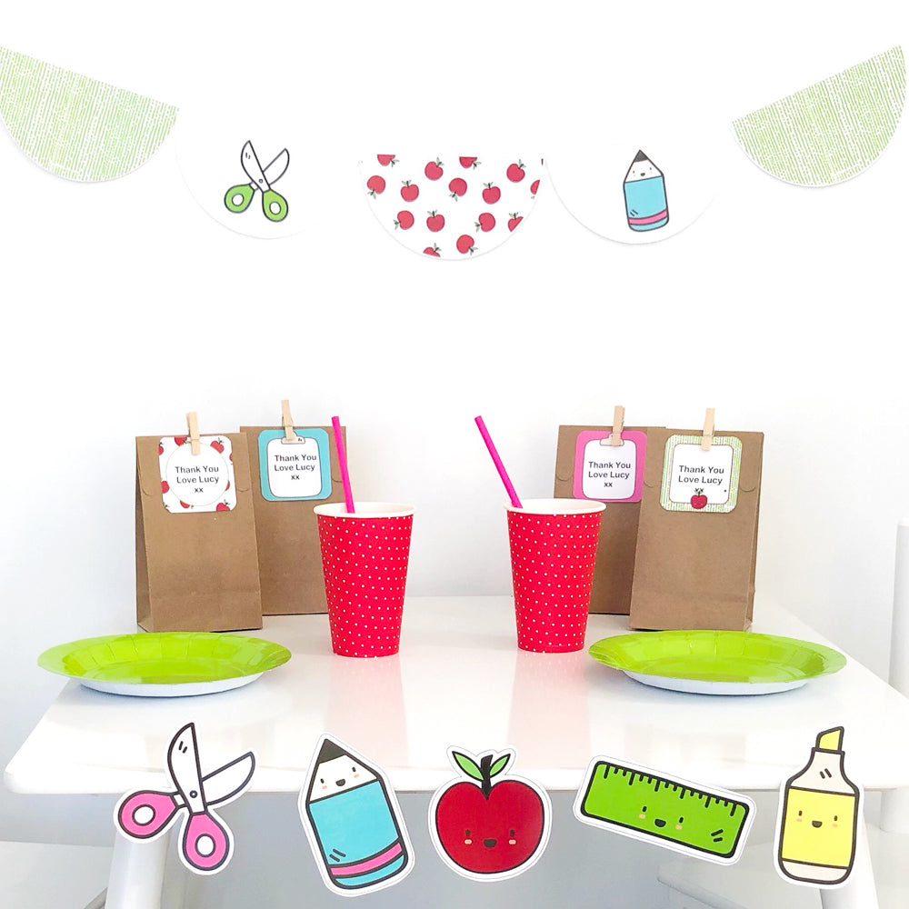 Children's party table setting with red cups, green plates, and educational-themed decorations.