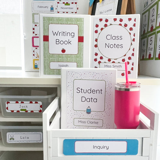 Educational materials including books and a pink cup on a white surface with storage drawers.