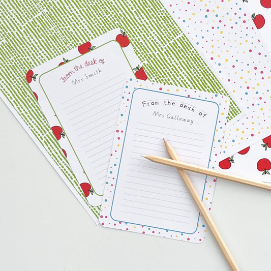 Note pads with apple design and 'From the desk of' text on a patterned background