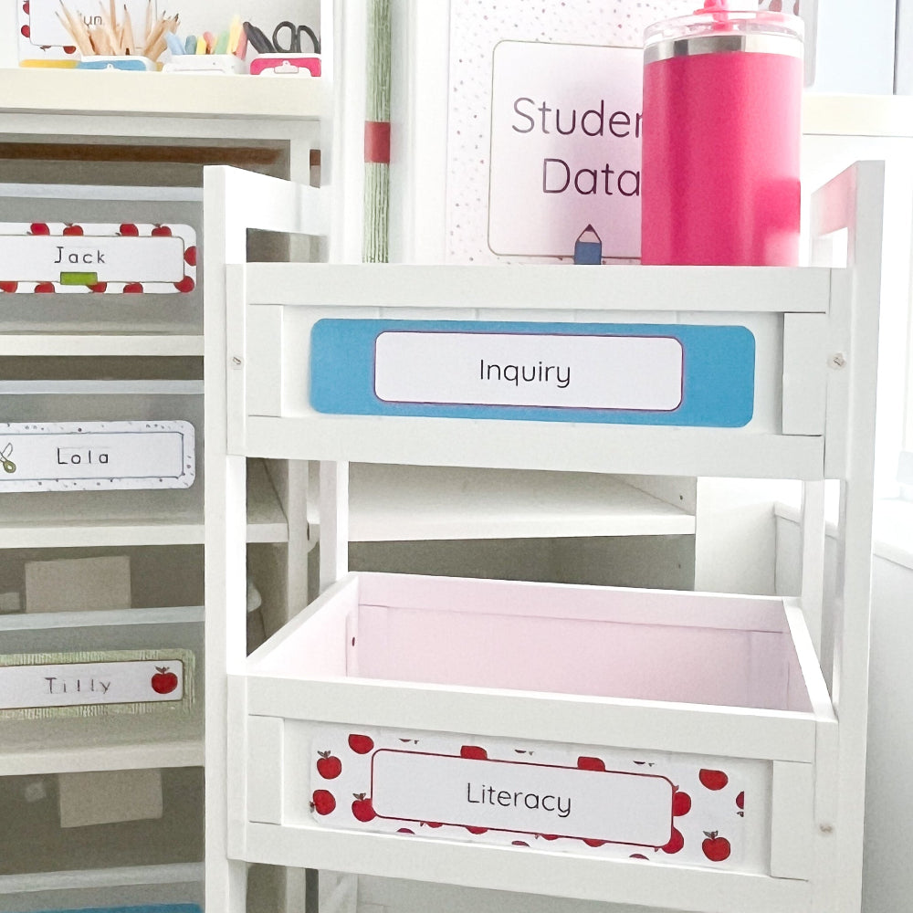 Educational classroom setup with labeled trolley drawers, a folder and a pink drink bottle.