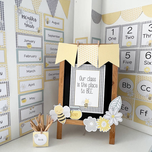 Educational classroom decor with a chalkboard, bee-themed decorations, and calendar on a white wall.