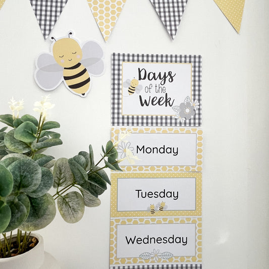 Educational children's poster with days of the week and a bee theme, placed on a white surface with decorative elements.