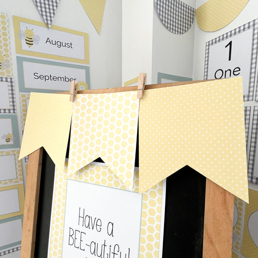 Yellow flag bunting displayed in classroom on blackboard easel. There are educational resources in the background.