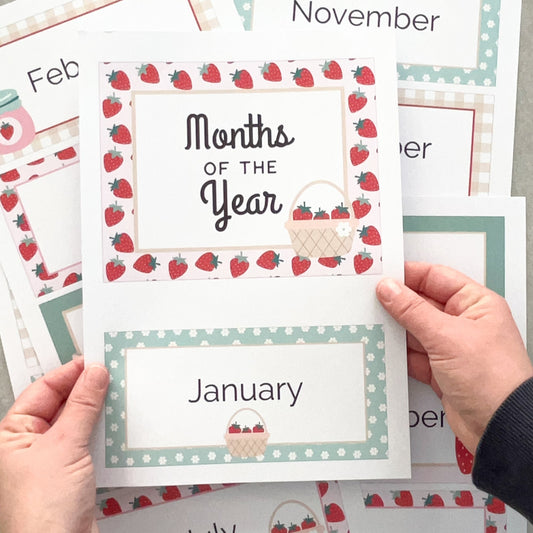 Sheet of months of the year cards with strawberry design held by a person.