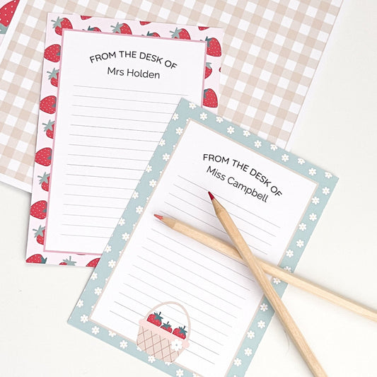 Set of personalised notepads with strawberry design and two pencils on a checkered background