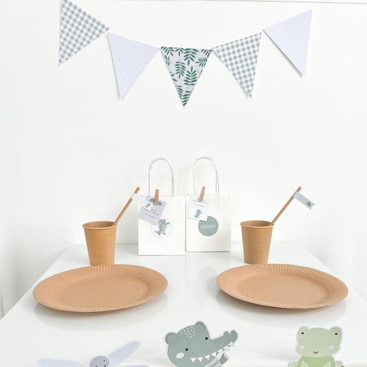 Crocodile Party Table Set up with triangle bunting and cups, plates and bowls on white table