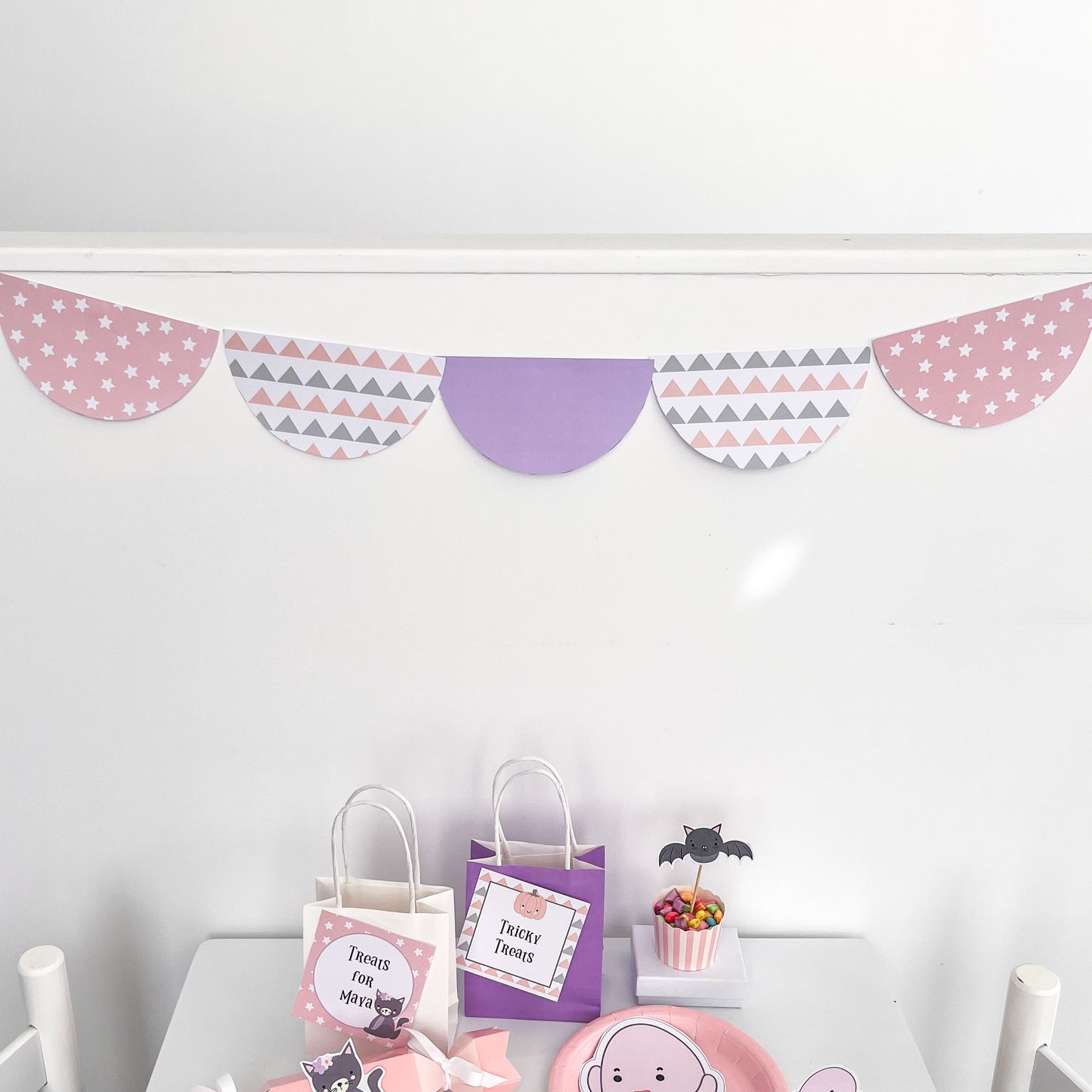 Pastel scalloped bunting for party on white wall displayed about halloween treat bags