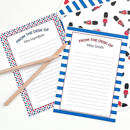 Two sheets of paper with decorative borders and text, accompanied by pencils on a white background.