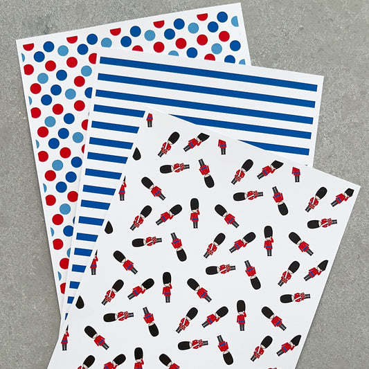 Three sheets of decorative stickers with red, blue, and black patterns on a grey background.