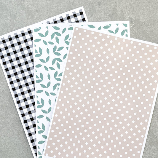 Three sheets of patterned paper with different designs that match a French Provincial farmhouse on a grey background