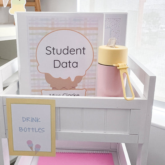 Pink water bottle with yellow lid on a white shelf next to a 'Student Data' teacher folder.
