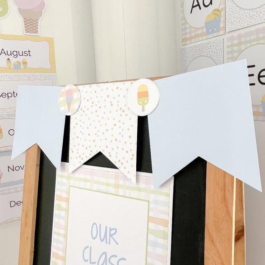 Decorative banner with ice cream-themed cutouts on a wooden frame against a wall with educational posters.