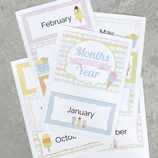 Set of educational cards with months of the year labels in pastel colours laid out on a gray surface
