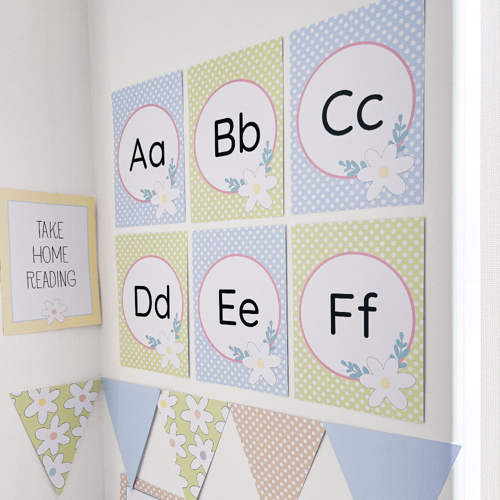 Pastel floral themed educational alphabet posters with letters A to F on a white wall.