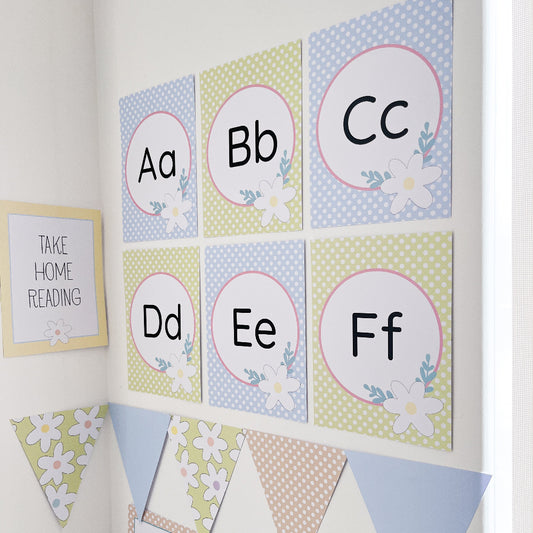 Pastel floral themed educational alphabet posters with letters A to F on a white wall.