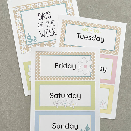 Pastel floral classroom charts with days of the week labels on a grey background