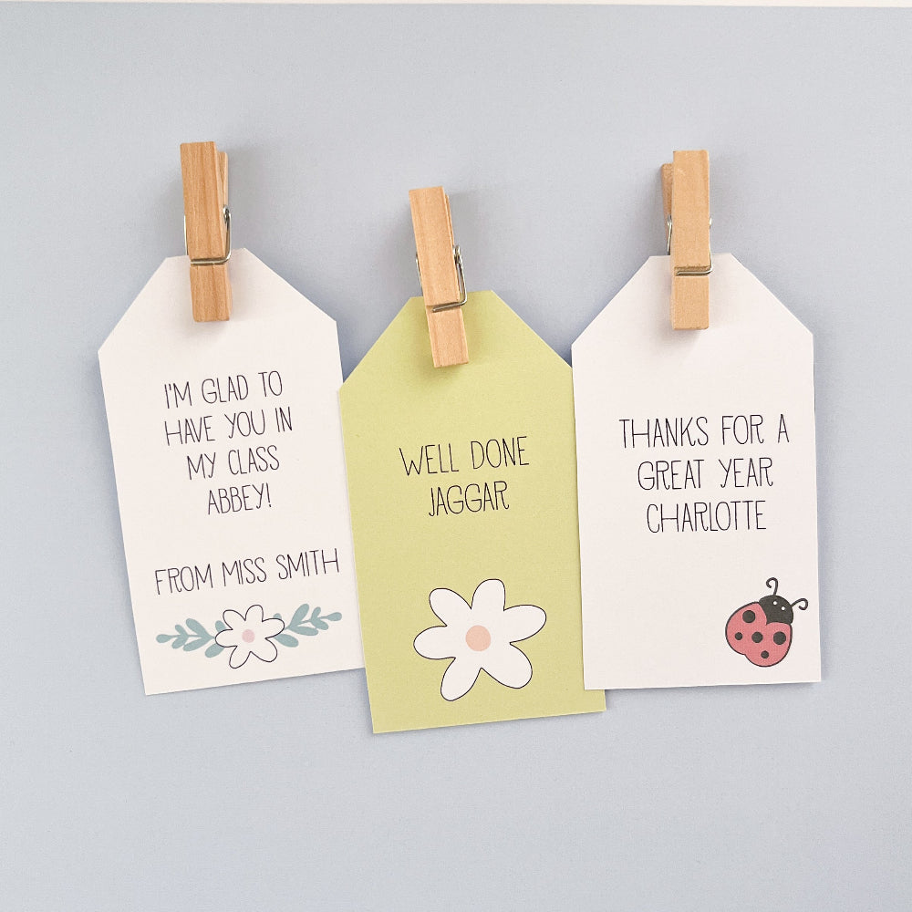 Three white tags with printed messages and designs, attached to a pale blue background.
