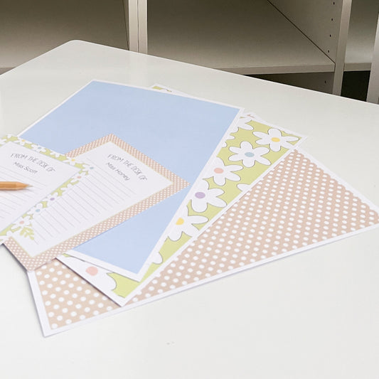 Stationery items including a pen, paper with floral designs, on a white surface.