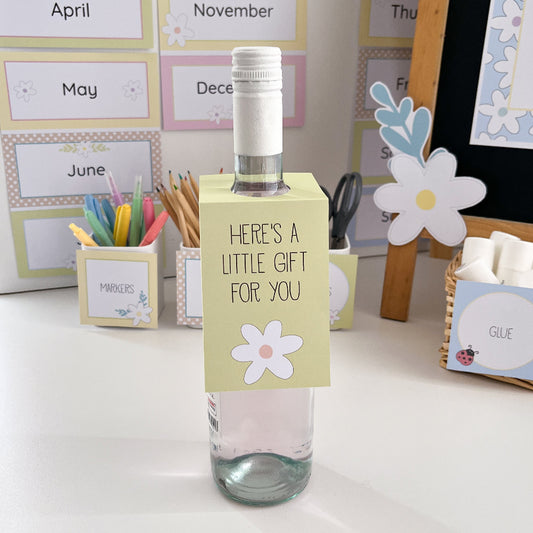 Clear bottle with a small gift tag attached, placed on a desk with stationery items.