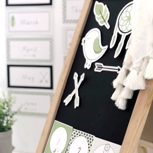 Classroom blackboard with bird, dreamcatcher, leaf and arrow cut outs in green and white.