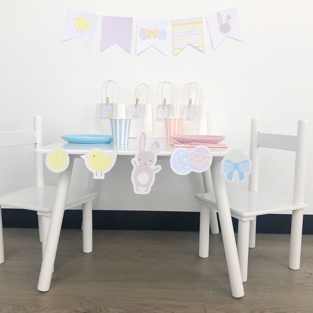 Easter celebration set up in pastel colours featuring printables and white table and chairs.