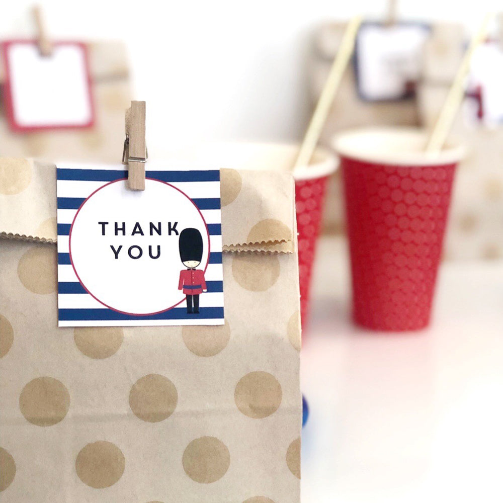 Square label featuring London Guard and stripes. The tag is attached to a party bag,