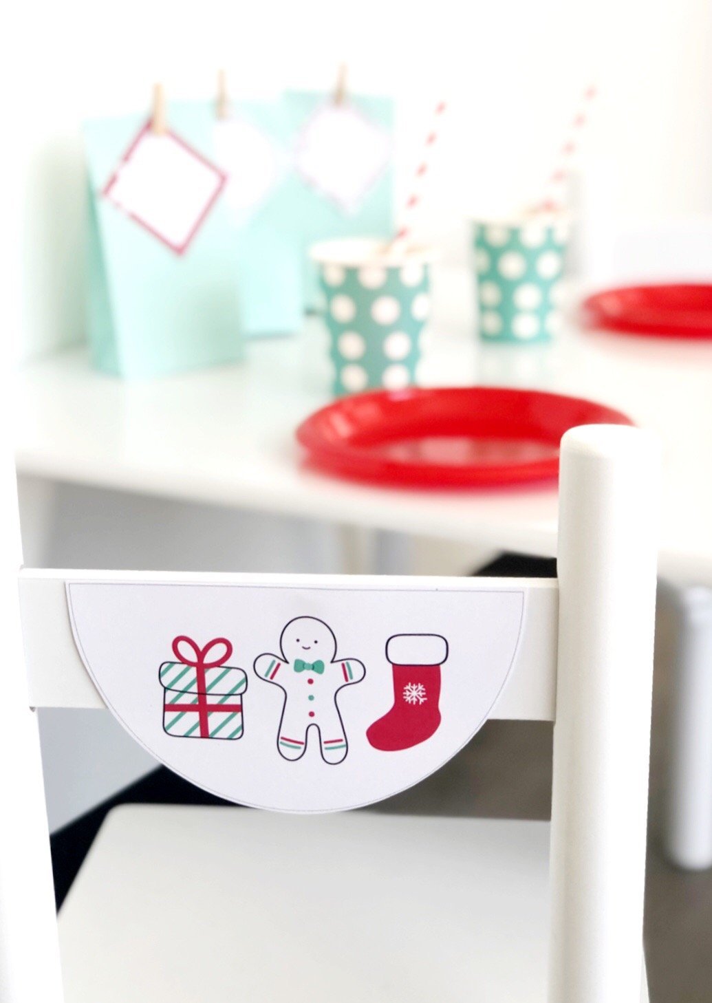 Christmas theme bunting flag on the back of a white chair. There is a party table set up in the background.
