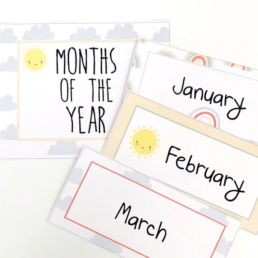 Educational cards with months of the year in a rainbow theme with cute sun graphics displayed on a white table.
