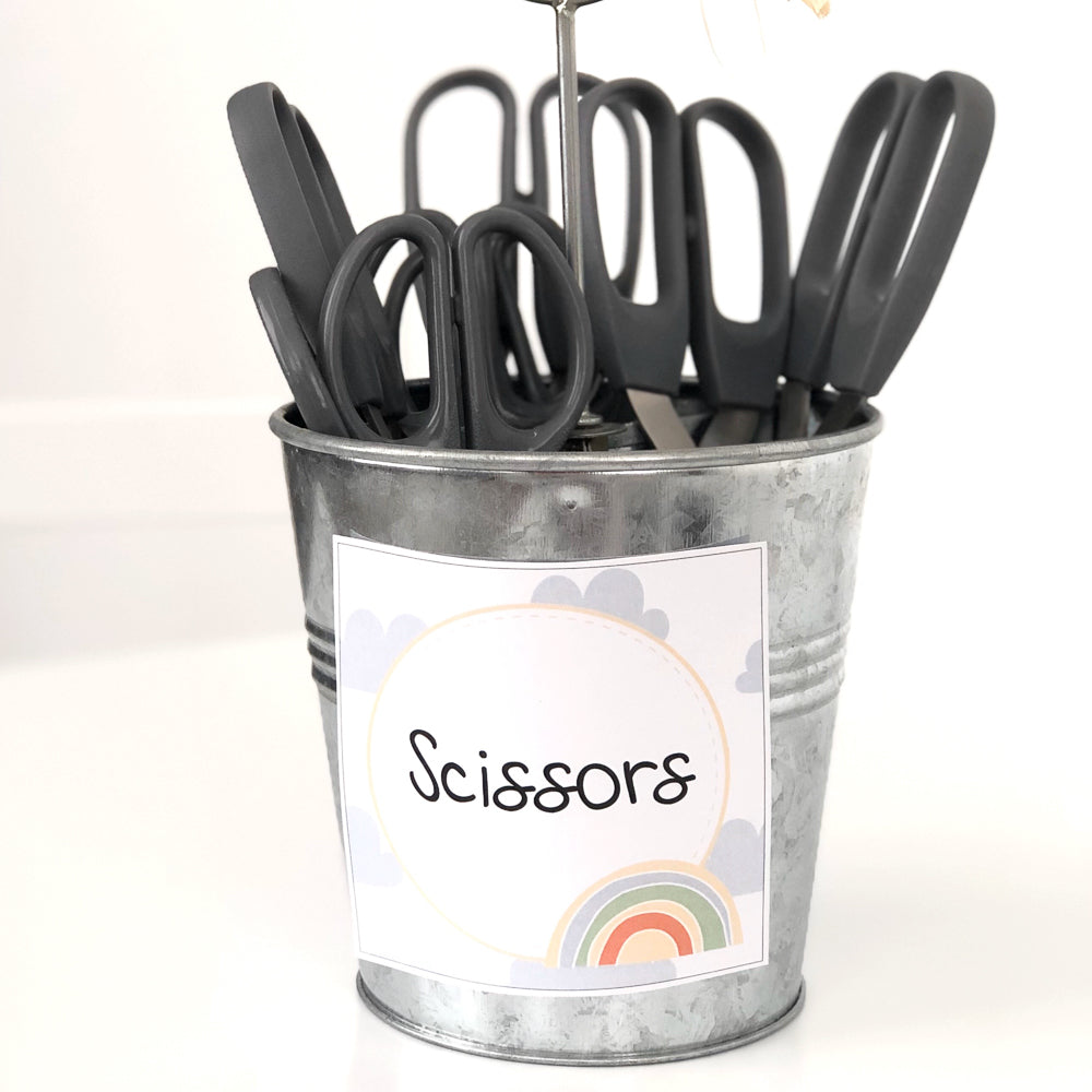 Scissors in a grey tin with a rainbow themed classroom label on a white background.