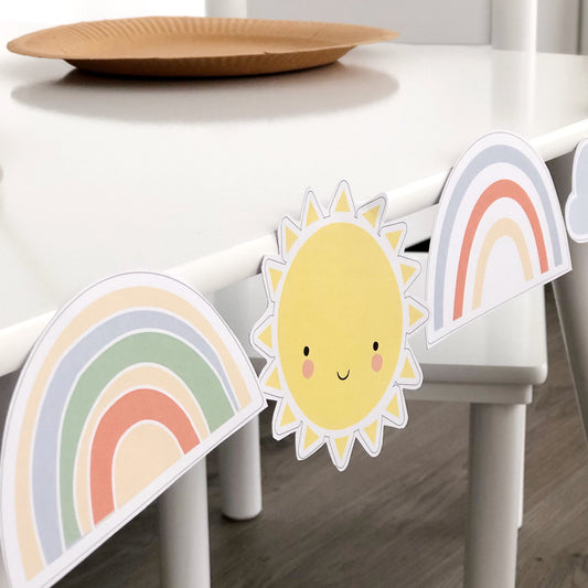 Rainbow and sun themed cut outs decorating a table for a party.