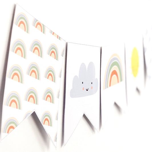 Rainbow themed bunting flags with cloud graphic on white wall.