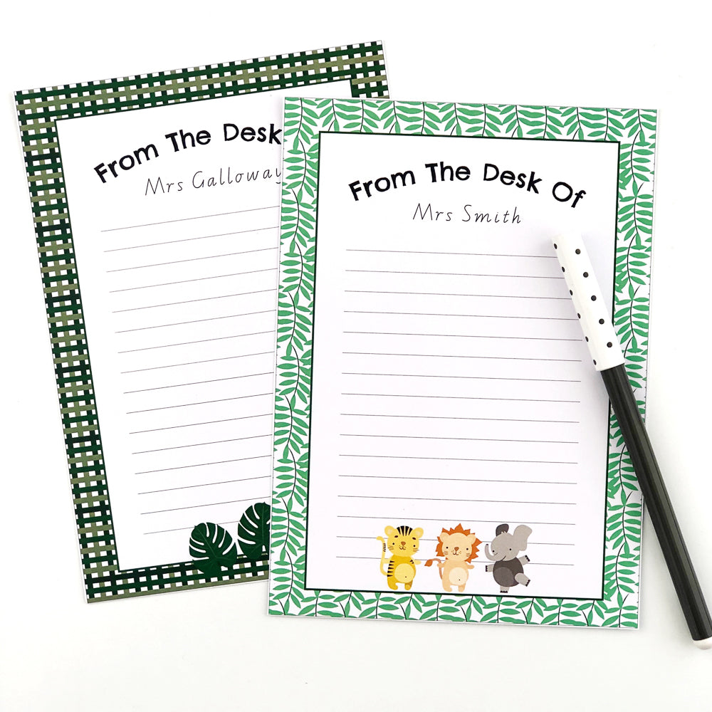 Safari themed editable note paper with cute safari animals and jungle leaves. Displayed next to a black pen on a white desk.