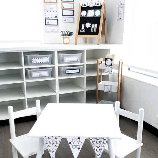 Science themed classroom set up with table, chairs, cubbyholes, teacher trolley and blackboard
