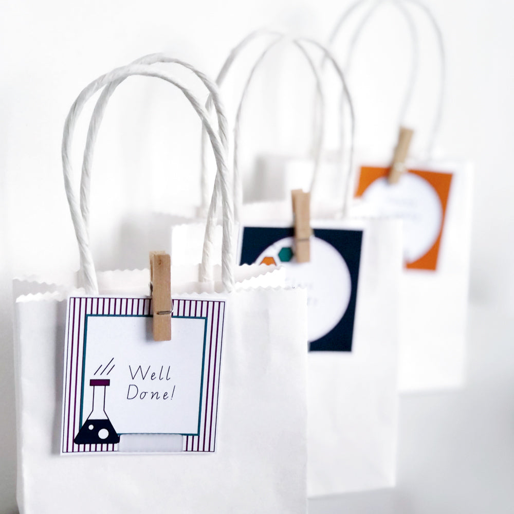 White party bags with science themed editable labels attached.
