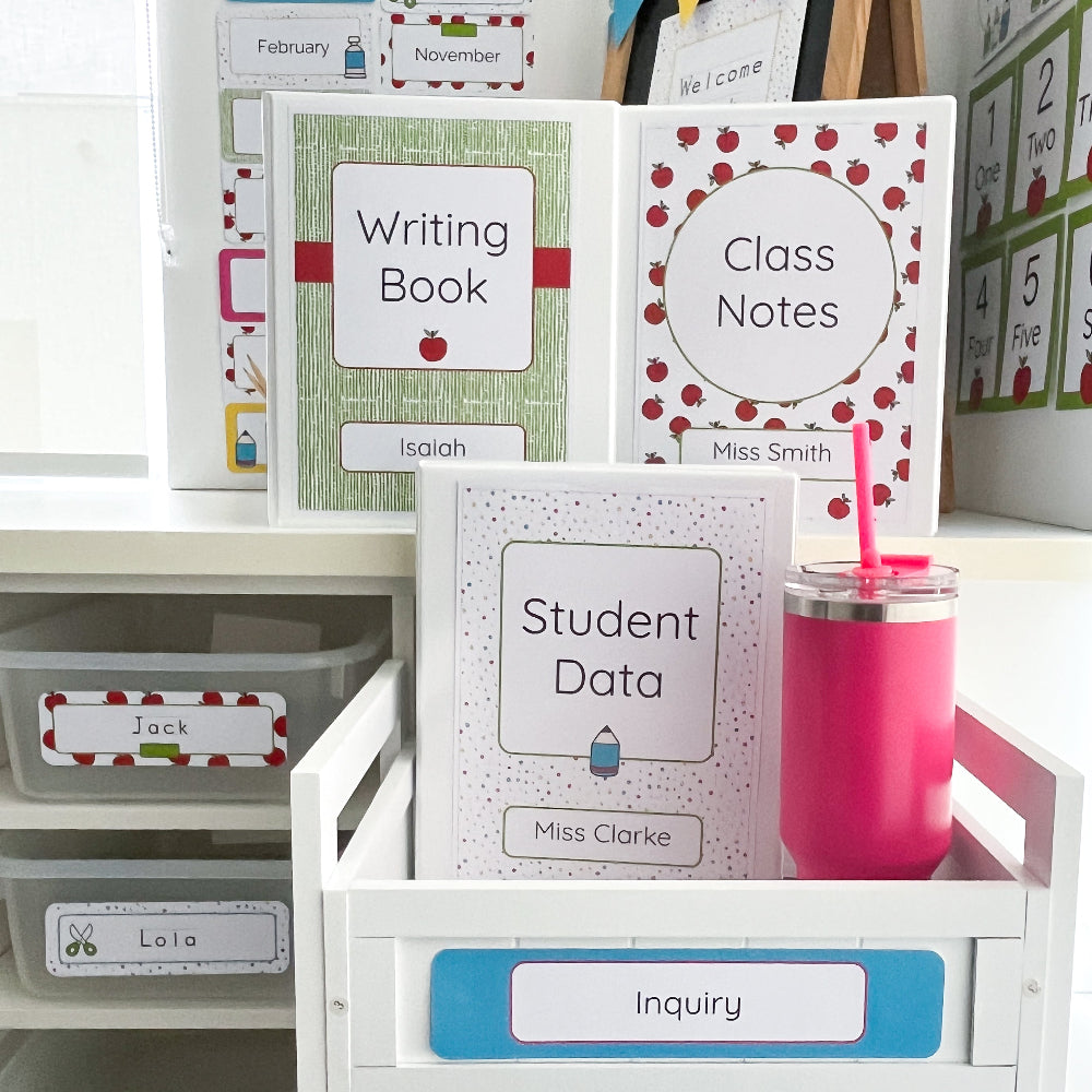 Educational materials including books and a pink cup on a white surface with storage drawers.
