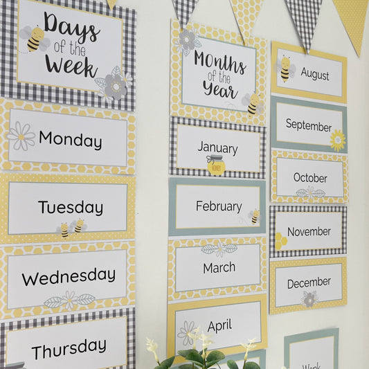 Educational posters in yellow and grey with a bee and flower theme displayed on white wall. 
