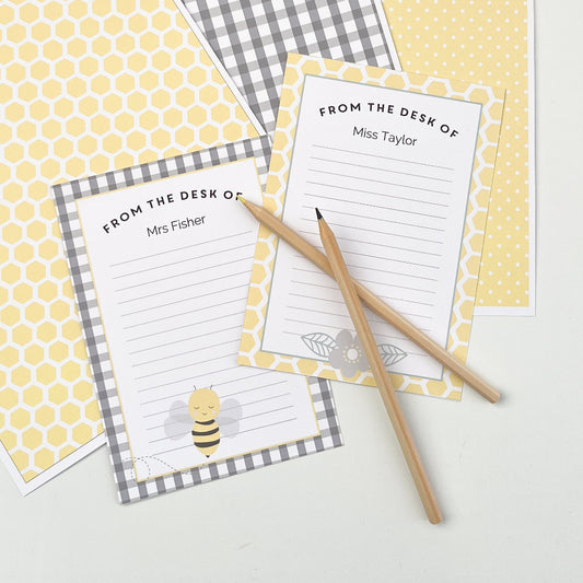 Sheets of personalised note paper and patterned papers displayed with pencils on a white table. 