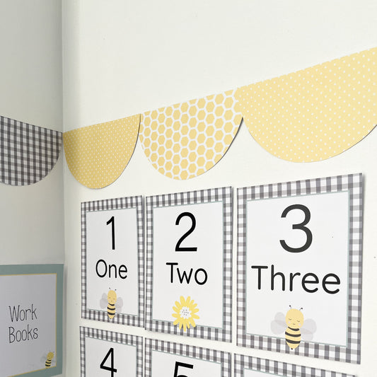 Educational children's numbers chart with bees and honeycomb design on a white wall.