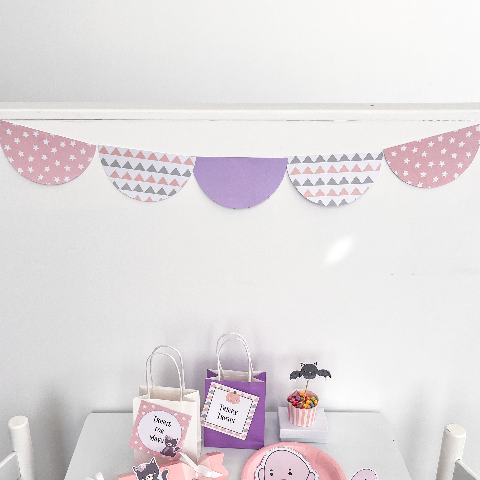 Pastel scalloped bunting for party on white wall displayed about halloween treat bags