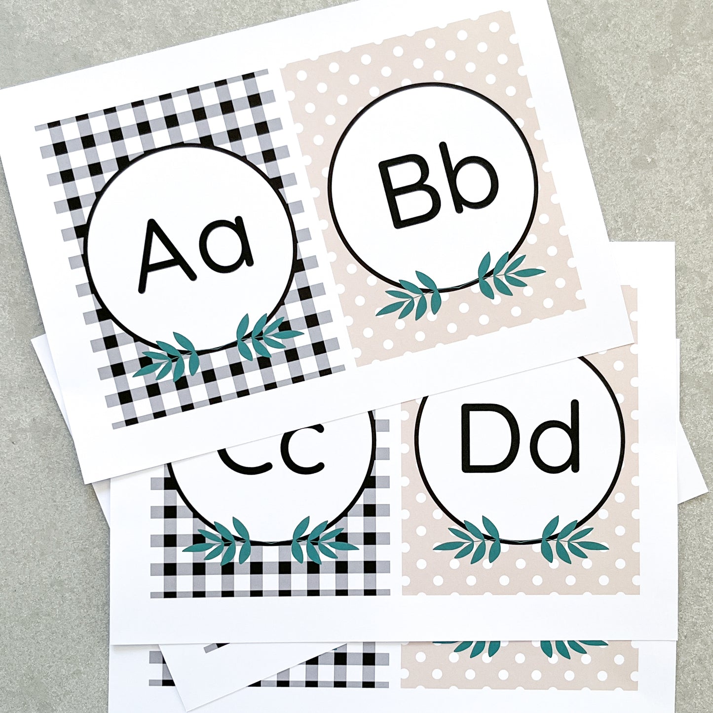 Classroom Alphabet Cards spread out on grety background. The letter A, B, C and D are on them with a leaf design, checks and polka dots. 