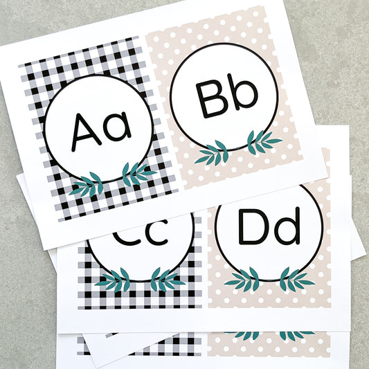 Classroom Alphabet Cards spread out on grety background. The letter A, B, C and D are on them with a leaf design, checks and polka dots. 