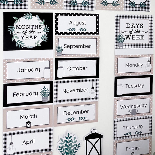Classroom charts featuring Months of the Year and Days of the week displayed on a white wall. They are coloured in black, white and beige. 