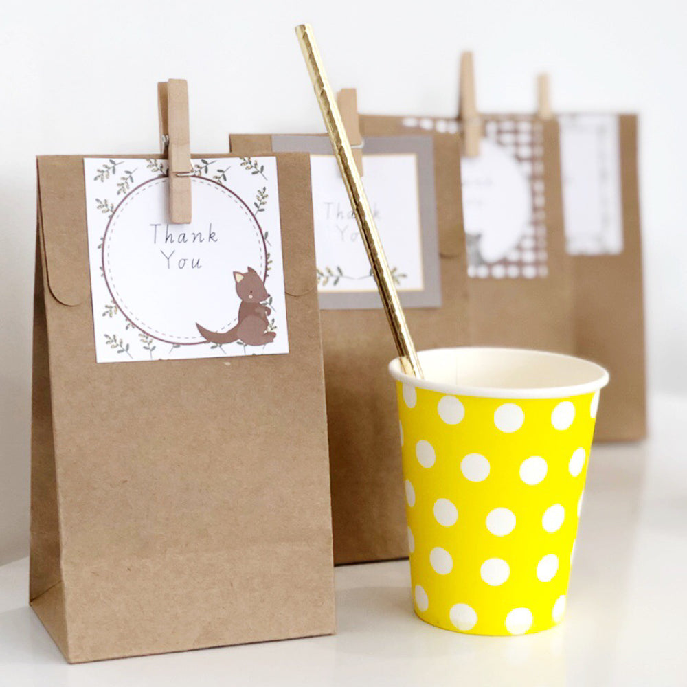 Brown party bags Australian Animal themed labels. There is a yellow polka dot cup next to them.