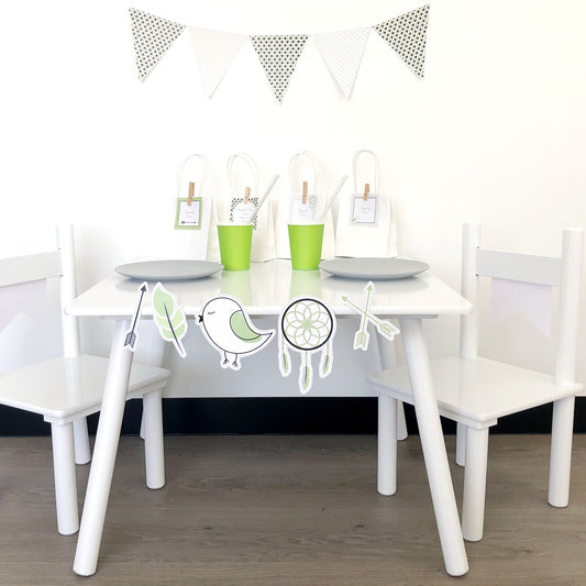 A set of mini party decoration printable files featuring bunting, triangles, flags, and boho icons displayed around a white table and chairs with green accents.