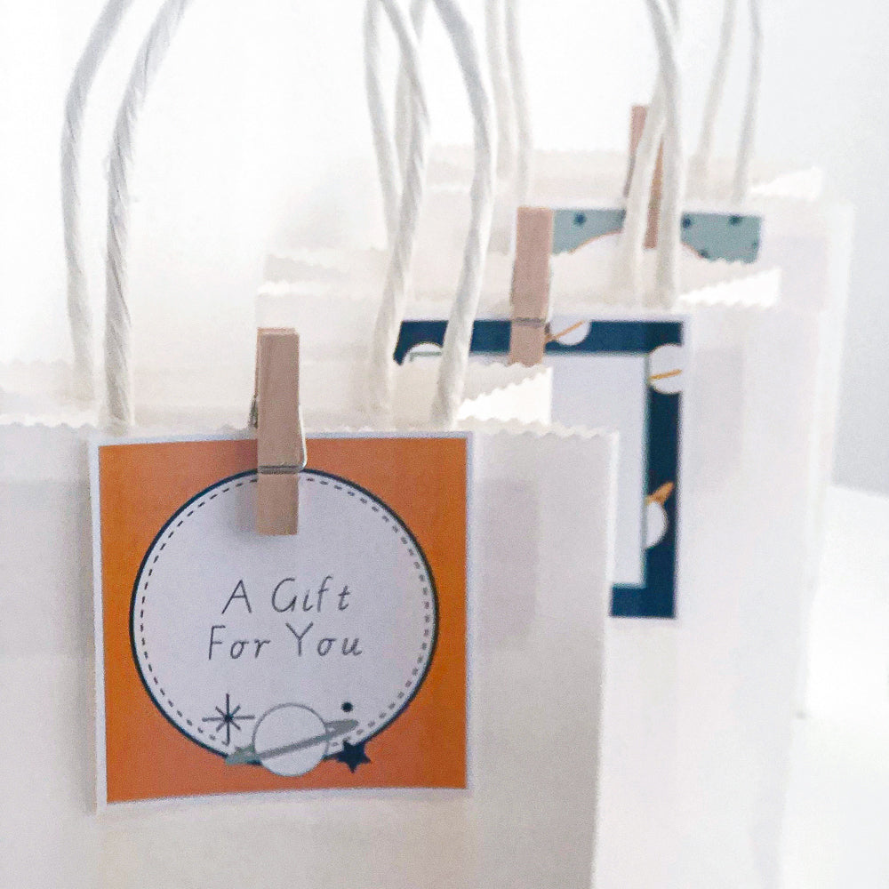 Space theme party gift bags with labels pegged onto the bags