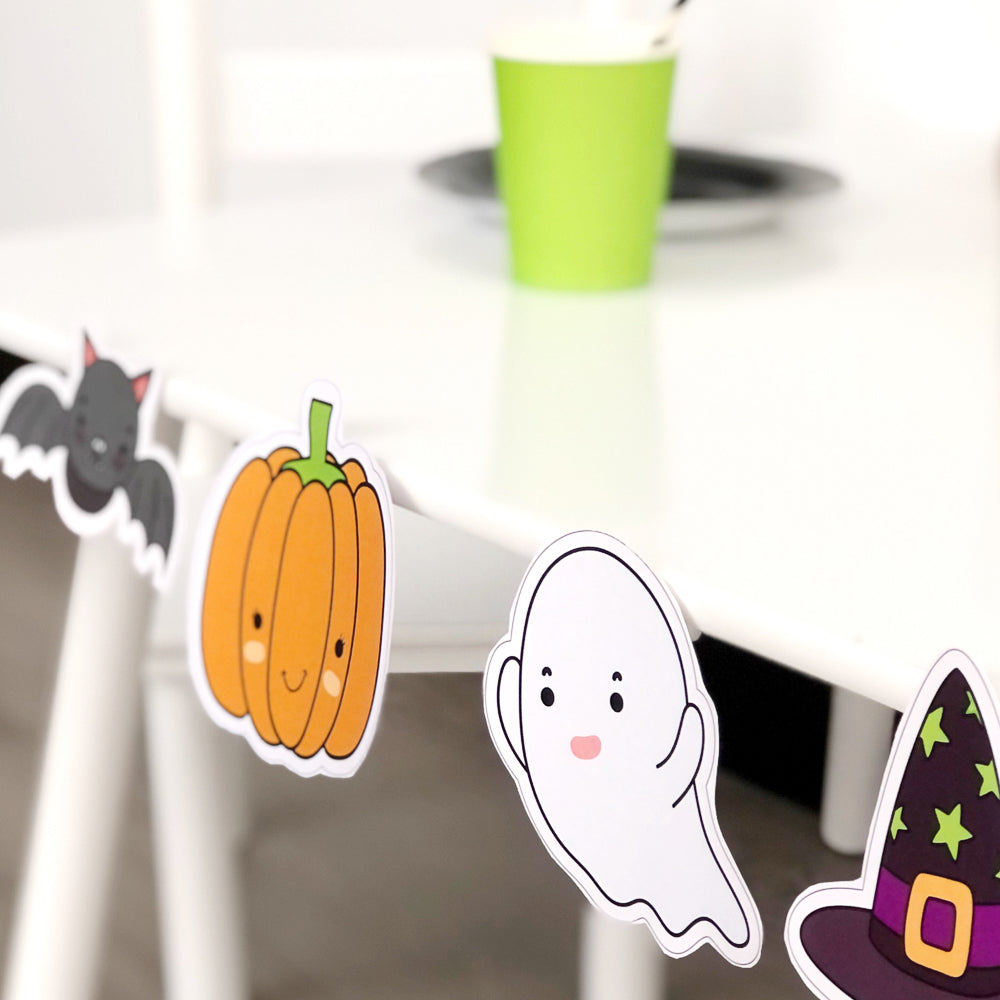 Halloween themed kids party set up on white table. Features pumpkin, bat, spider web and ghost. 