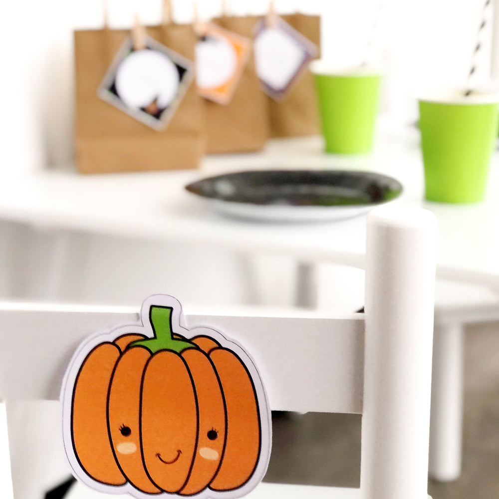 Cute orange Halloween Pumpkin printable displayed on white chair as a party table set up decoration.