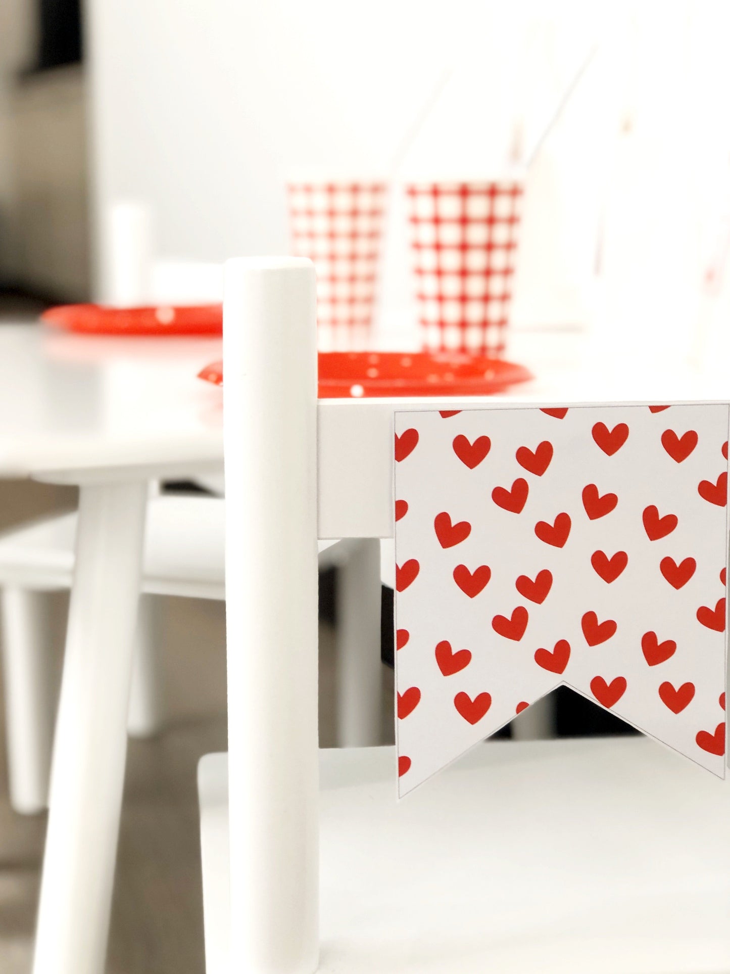 Cute valentines day bunting flag on chair with party set up in background.