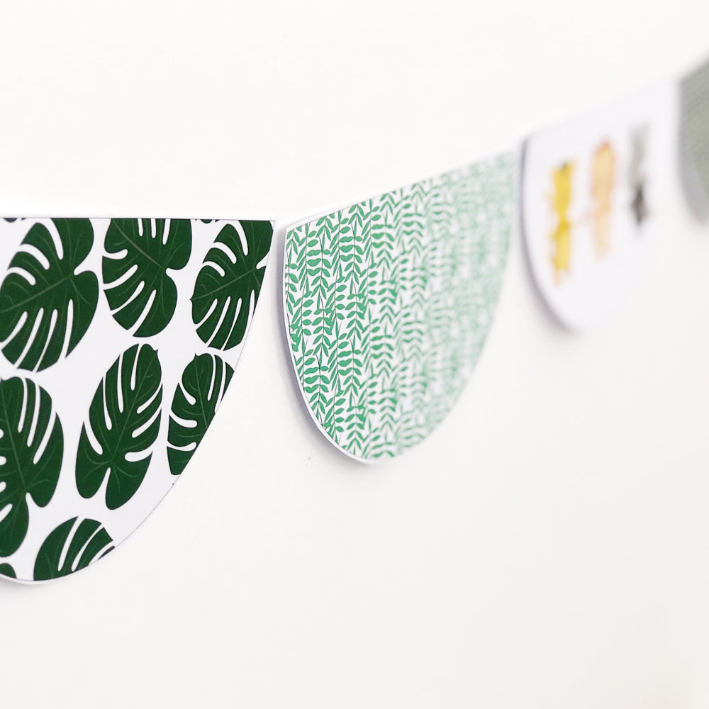 Scalloped Bunting shape with  green leaf patterns displayed on a white wall 